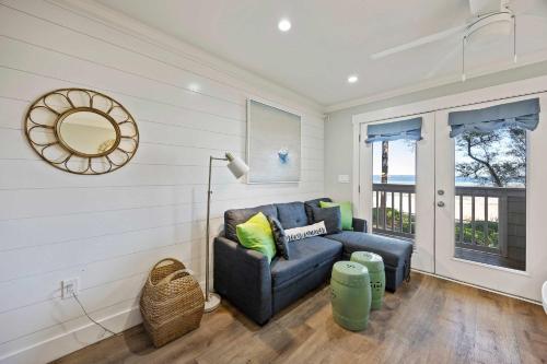 een woonkamer met een blauwe bank en een spiegel bij Oceanfront Sunrises on Mitchelville Beach in Hilton Head Island