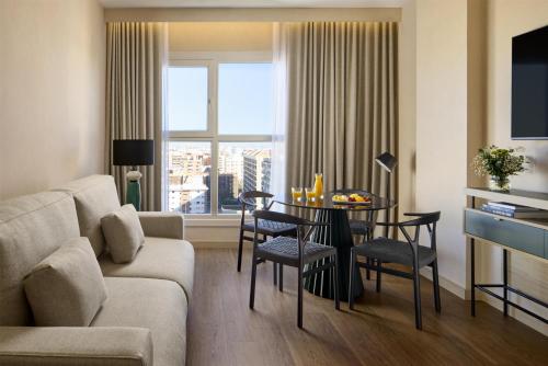 a living room with a couch and a table with chairs at NH Valencia Center in Valencia