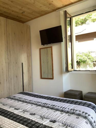a bedroom with a bed and a television on the wall at Fuga dalla città in Grosotto