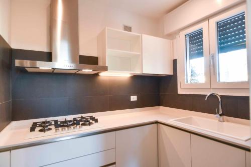 a white kitchen with a stove and a sink at CasaTitti Polcenigo in San Giovanni