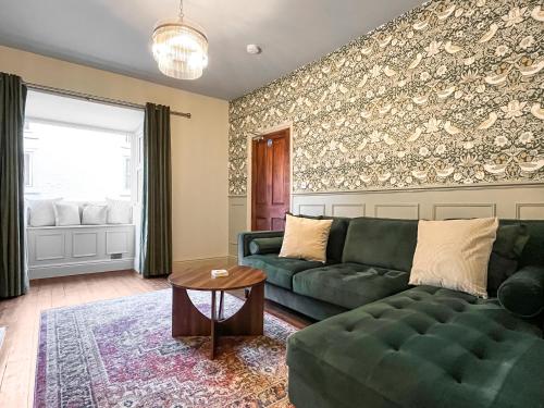 ein Wohnzimmer mit einer grünen Couch und einem Tisch in der Unterkunft Botany Bay House in Whitby