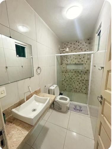 a white bathroom with a sink and a toilet at Casa Maragogi in Maragogi