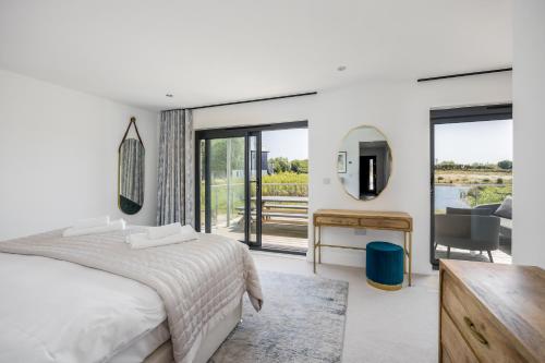 ein Schlafzimmer mit einem Bett und einem Schreibtisch mit Spiegel in der Unterkunft Knighton - Luxury Dorset lakeside home, sleeps 12 with spa and pool access in Warmwell