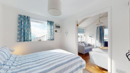 a bedroom with a striped bed and a living room at D22 Sandelite, Riviere Towans in Hayle