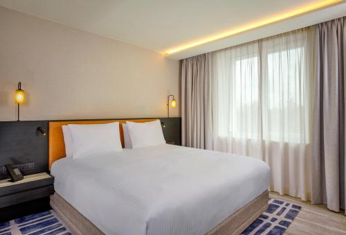 a bedroom with a large white bed and a window at Courtyard by Marriott Ghent in Ghent