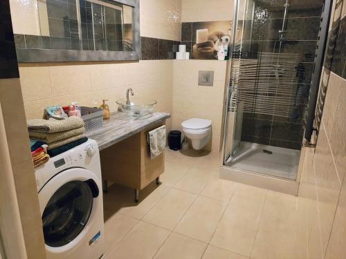 a bathroom with a washing machine and a shower at Apartament na Chmielnej in Rychwał