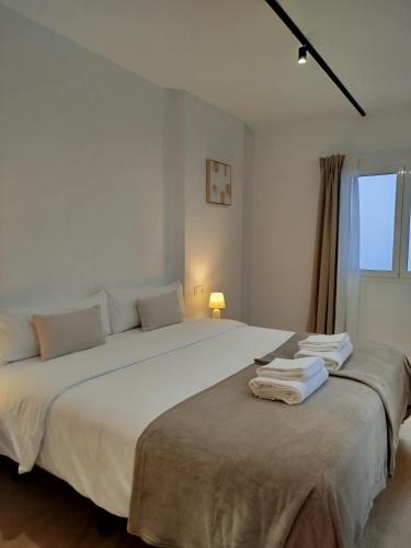 a bedroom with a large white bed with towels on it at TAYP Sol 120 in Seville