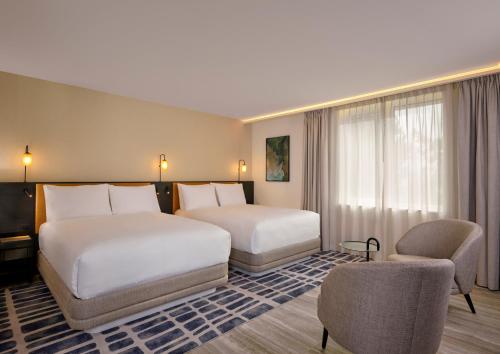 a hotel room with two beds and a chair at Courtyard by Marriott Ghent in Ghent