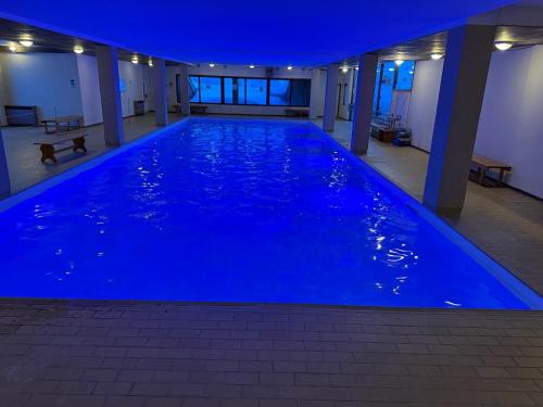 a large blue swimming pool in a building at night at Top Residence Trilocale Larice in Passo del Tonale