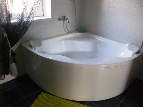 a white bath tub in a bathroom with a window at Home for Guests Lakštingala in Šiauliai