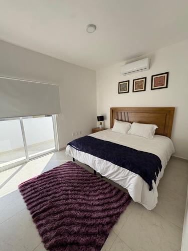 a bedroom with a large bed with a purple rug at La casa blanca in Mezcales