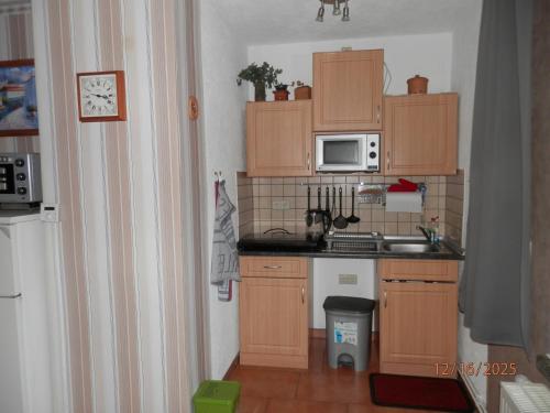 een kleine keuken met houten kasten en een spoelbak bij Ferienwohnung bei Familie Keil in Colditz