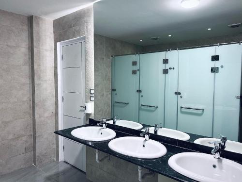 a bathroom with three sinks and a shower at Rafiki Hostels - Pyramids in Giza