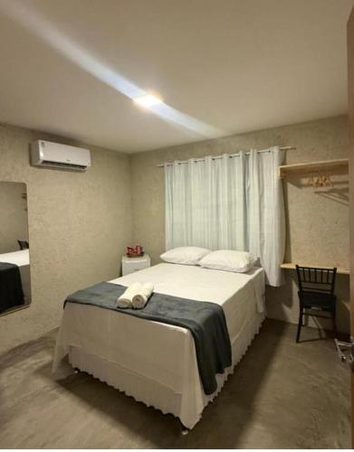 a bedroom with a large white bed with a window at Pousada Arena 165 in Murici