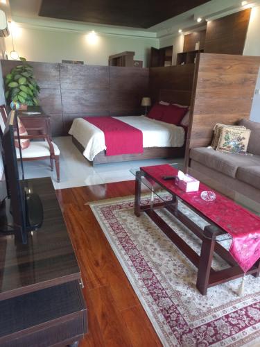 ein Schlafzimmer mit einem Bett, einer Couch und einem Tisch in der Unterkunft Executive Studio Apartment Lahore in Lahore