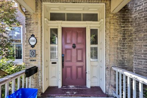 une porte rose sur une maison en briques avec un porche dans l'établissement Spacious 1 bed 1 bath Apt Close to Downtown and Beach, à Cobourg