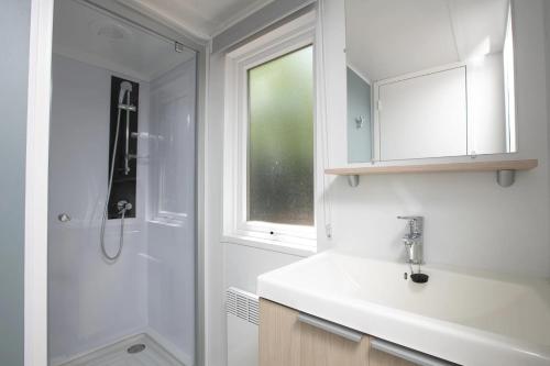 een witte badkamer met een wastafel en een douche bij Camping 4 étoiles - Piscine - eeihec in Loupiac