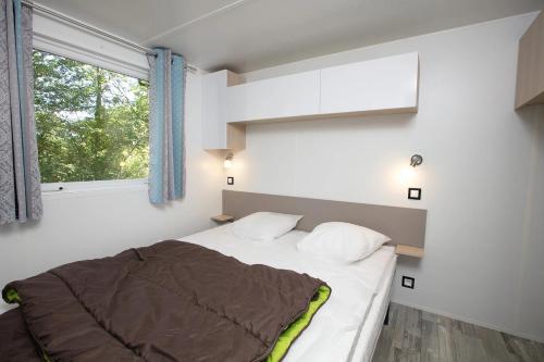 een kleine slaapkamer met een bed en een raam bij Camping 4 étoiles - Piscine - eeihec in Loupiac