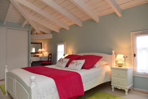een slaapkamer met een groot wit bed met rode kussens bij La cheneraie in Mano