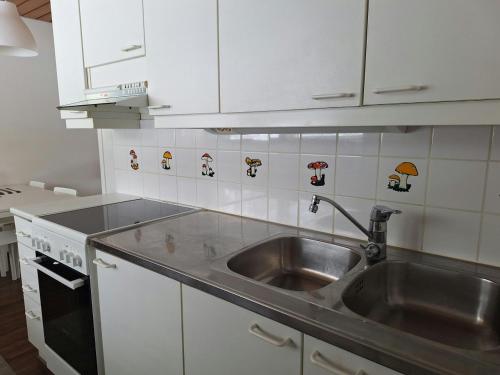 a kitchen with a stainless steel sink and white cabinets at Spacious Apartment for 5 in Sodankylä
