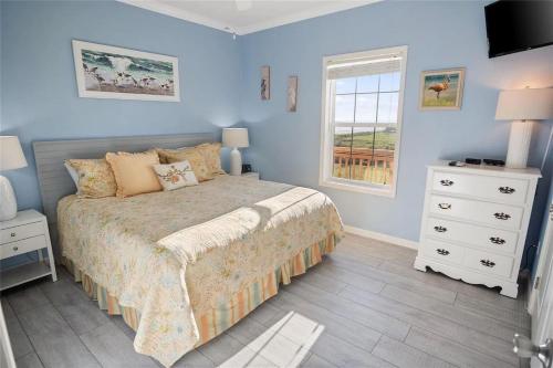 a blue bedroom with a bed and a window at Beachfront Home with Huge Deck in Bolivar Peninsula
