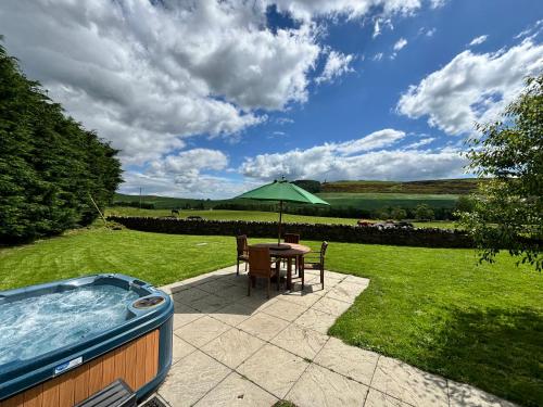 a patio with a table and an outdoor hot tub at East Cottage at Parbroath Farm in Cupar
