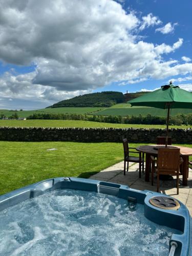 a swimming pool with a table and an umbrella at East Cottage at Parbroath Farm in Cupar