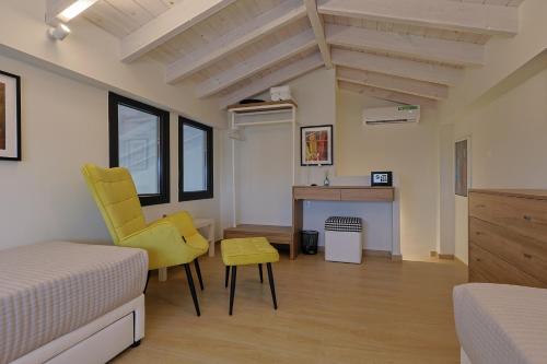 una camera da letto con sedia gialla e scrivania di HELIOS - Seaside Pool Villa & Private Parking a Olympiakí Aktí