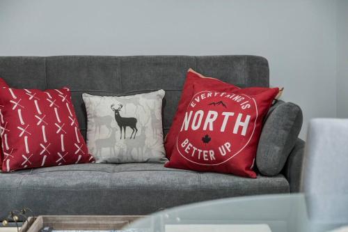 a gray couch with red pillows on it at Cozy Mountain View Condo Close to DT Canmore in Canmore