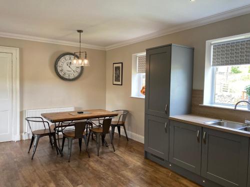 a kitchen with a table and a clock on the wall at East Cottage at Parbroath Farm in Cupar