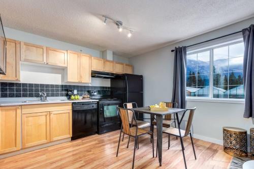 a kitchen with a table and chairs and a kitchen with black appliances at Delightful 2BR Mountain Escape in Canmore in Canmore