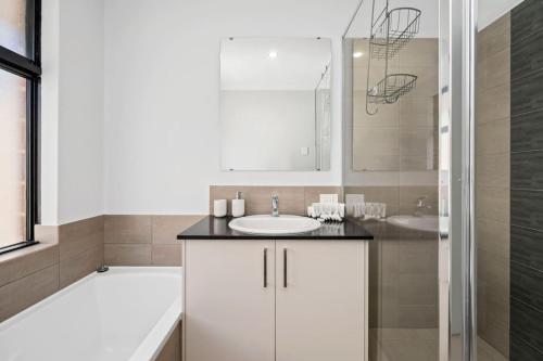 a white bathroom with a sink and a shower at The Sunlit Expansive Hideaway in Alkimos