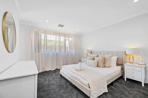 a white bedroom with a large bed and a mirror at The Sunlit Expansive Hideaway in Alkimos