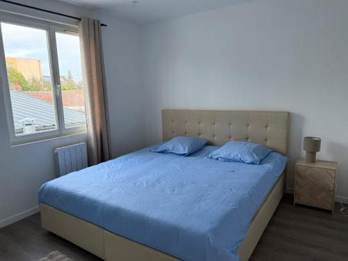 ein Schlafzimmer mit einem Bett mit blauen Laken und einem Fenster in der Unterkunft Le prestige - Charmant T2 neuf avec Terrasse in Évreux