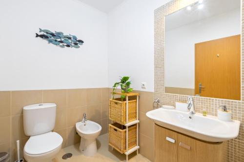 a bathroom with a toilet and a sink and a mirror at Cabanas Beach T2 in Cabanas de Tavira