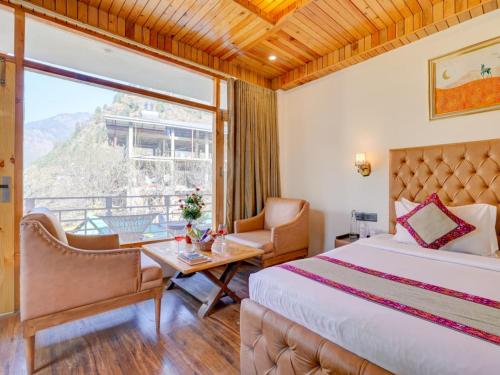 a bedroom with a bed and a table and a window at Omavya luxury hotel & cottage -with bonfire , apple orchid ,mountain view , parking in Vashisht