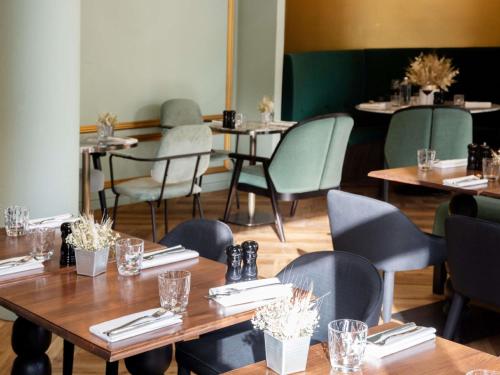 マフリエにあるHotel Novotel Domaine de Maffliers - Paris Val-d'Oiseの木製のテーブルと椅子のあるダイニングルーム