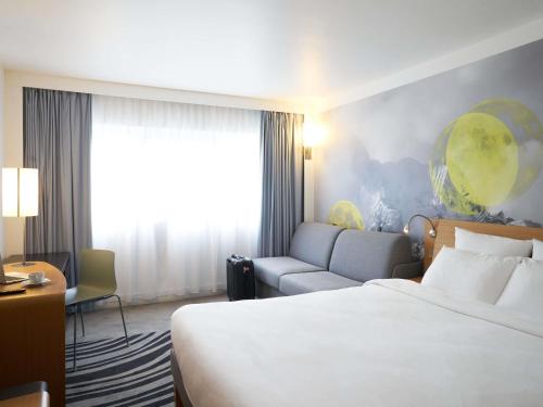 a hotel room with a bed and a couch at Novotel Marne La Vallée Collégien in Collégien