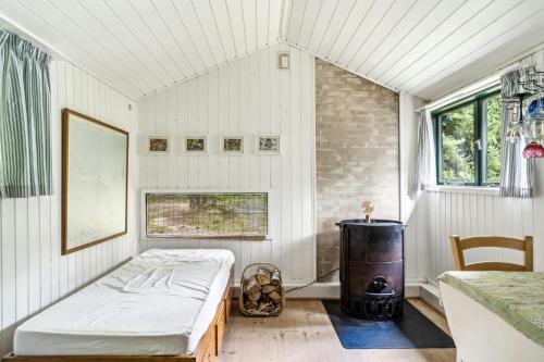 Un dormitorio con una cama y una estufa dentro. en Summer House With Large Nature Plot In Rørvig, en Rørvig