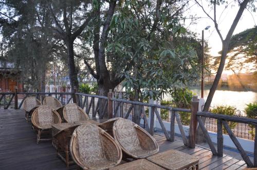 a row of chairs sitting on a deck near the water at Trinity Family Inn in Nyaung Shwe