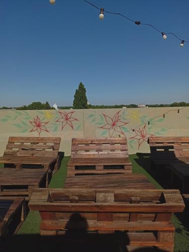 a group of wooden benches in front of a mural at Alojamiento Avellaneda in Rosario