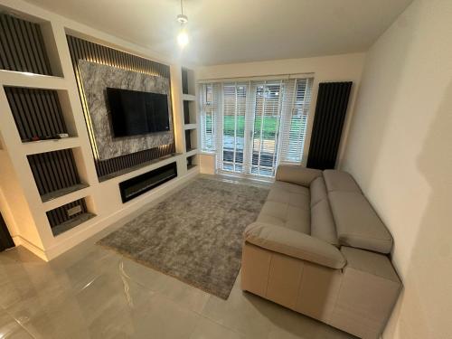 een woonkamer met een bank en een flatscreen-tv bij Hendham Lodge in Manchester