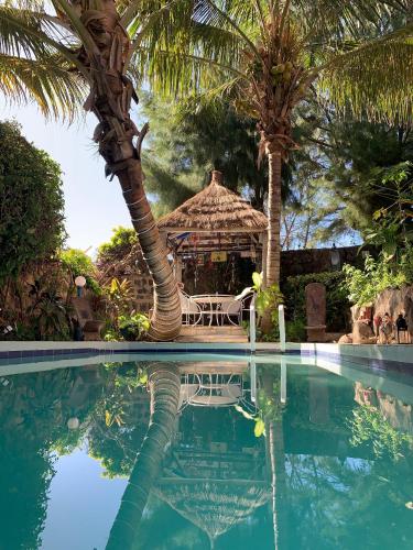 a resort swimming pool with a gazebo and palm trees at Fabuleuse Villa Keur Bibou in Dakar