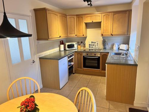 een keuken met houten kasten en een tafel met een kom bloemen bij Seaview Terrace - Beer in Beer