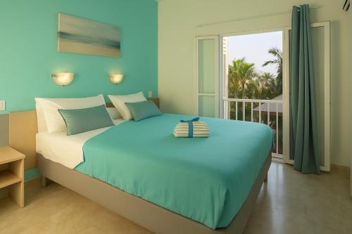 ein blaues Schlafzimmer mit einem Bett und einem Fenster in der Unterkunft Maspalomas Green Oasis 1404 in Maspalomas