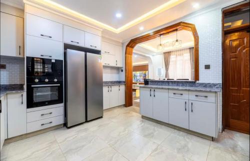 a kitchen with white cabinets and a black refrigerator at Emerald Greens 3-Bedroom House in Thika