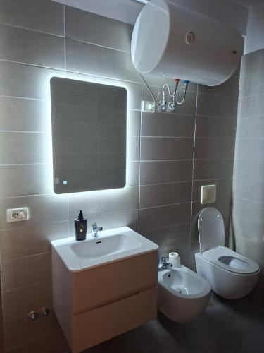 un bagno con lavandino, WC e specchio di Heart Apartment Tirana a Tirana
