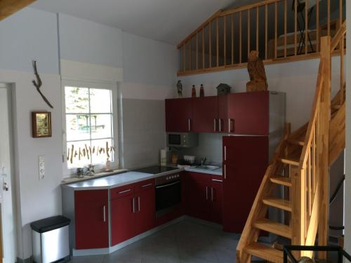 een keuken met rode kasten en een trap bij Ferienhaus am Fleesensee in Silz
