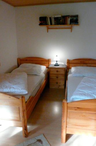a bedroom with two beds and a night stand with a lamp at Ferienhaushälfte Fleesensee in Silz
