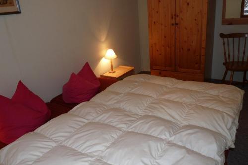 un letto bianco con cuscini rossi in una stanza di Ferienhaus beim Stechlinsee a Neuglobsow